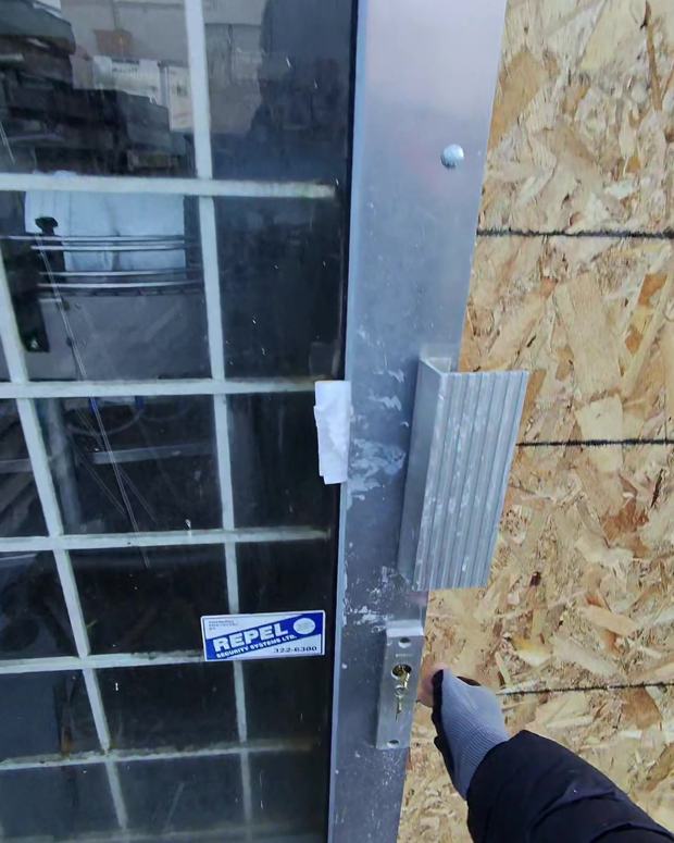 Emergency plywood board-up over a broken storefront glass door