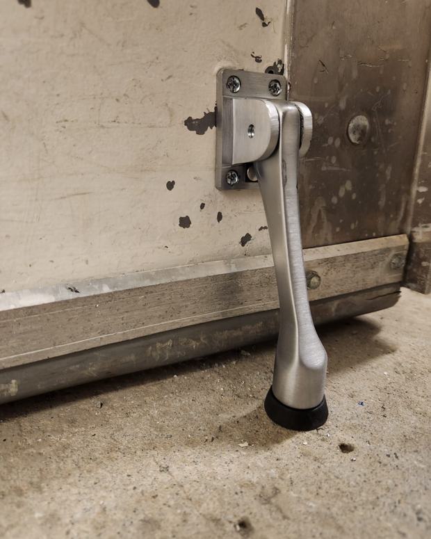 Floor-mounted door holder installed at a commercial service entrance