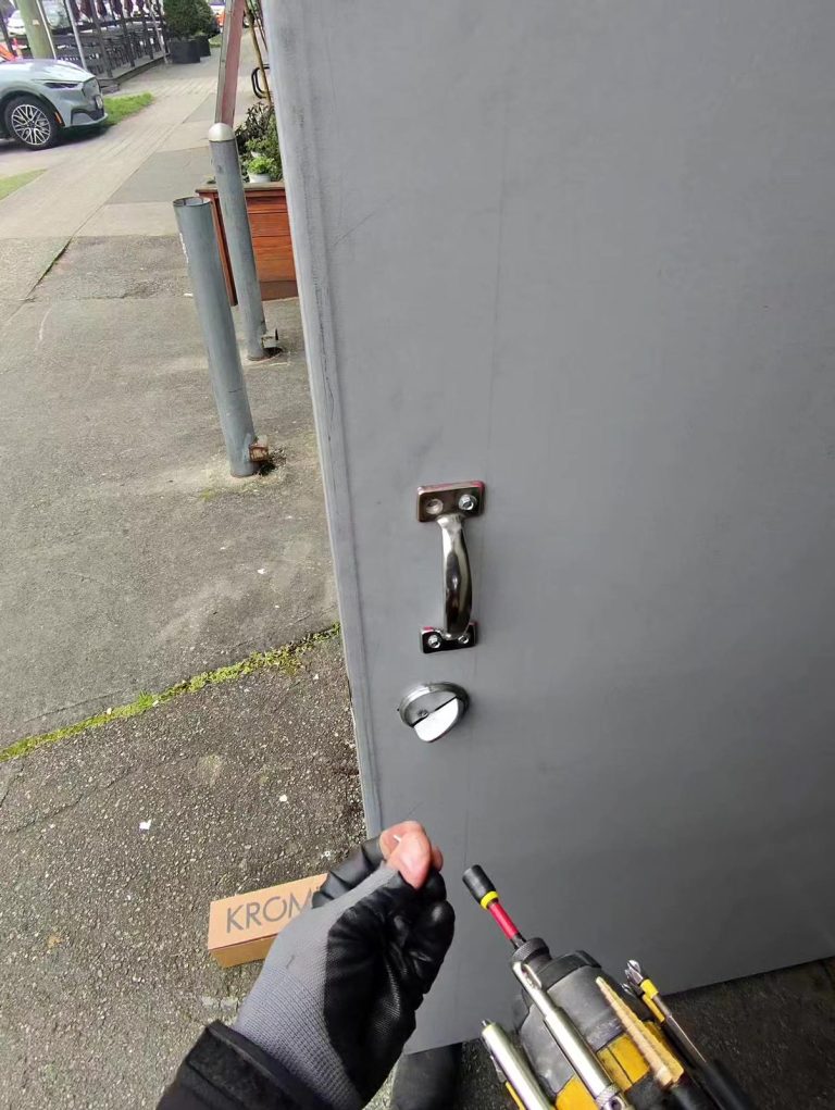 Stainless pull handle and keyed deadbolt newly installed on a grey commercial side entrance door