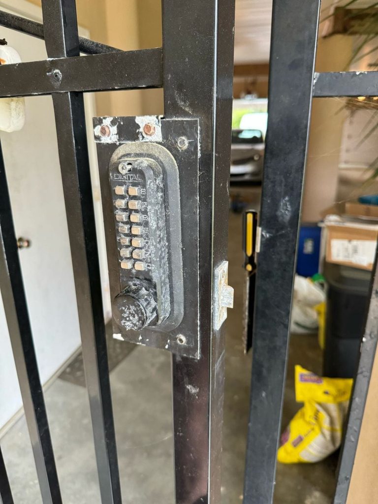 Push-button keypad deadbolt mounted on a black wrought iron side gate