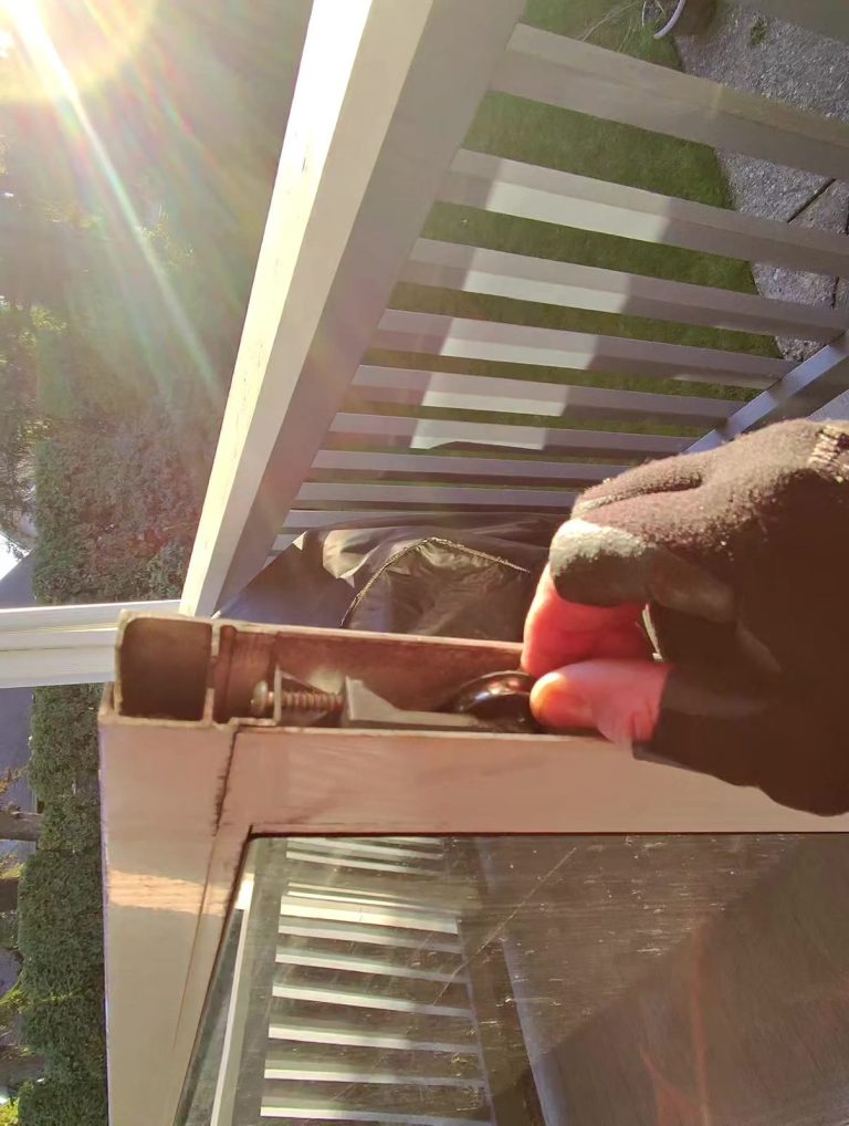 Close-up of the roller assembly on the frame of a sliding patio screen door during repair